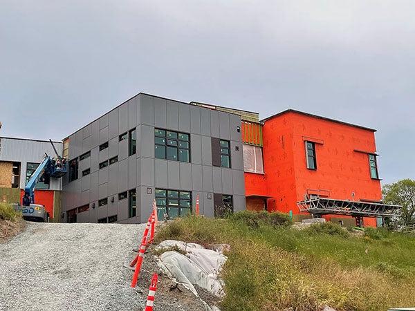 a 2 story building on a hill -- half gray, half orange